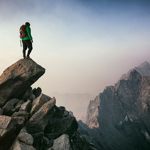 Photo d'un homme au sommet d'une montagne, symbolise la réussite, le cheminement, la vie, le sommet.